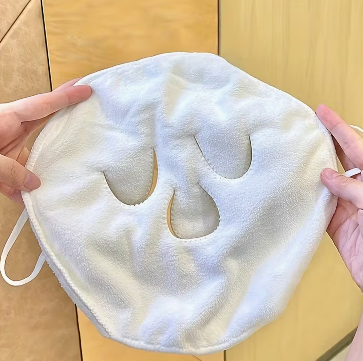 Woman wearing beige hot and cold compress face towel mask